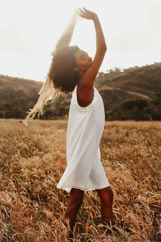 a girl poses in the field as she holds her hands back