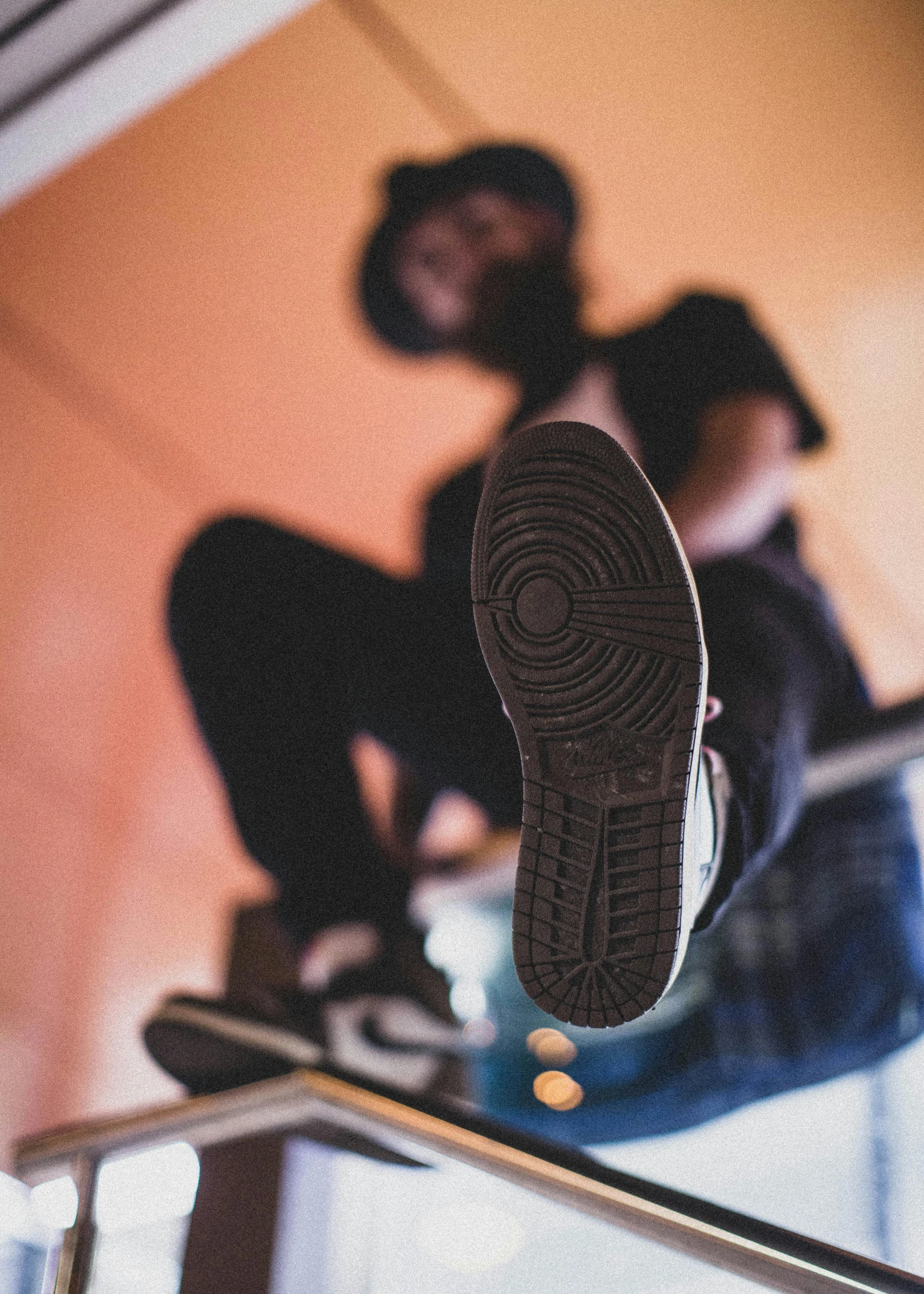 man sitting down on his skateboard while a person rides a stair rail