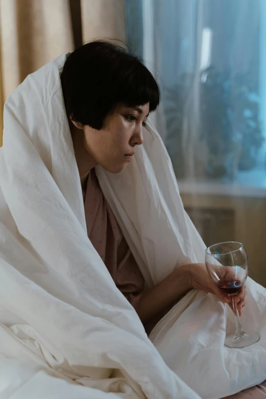 a woman sitting on a bed holding a wine glass