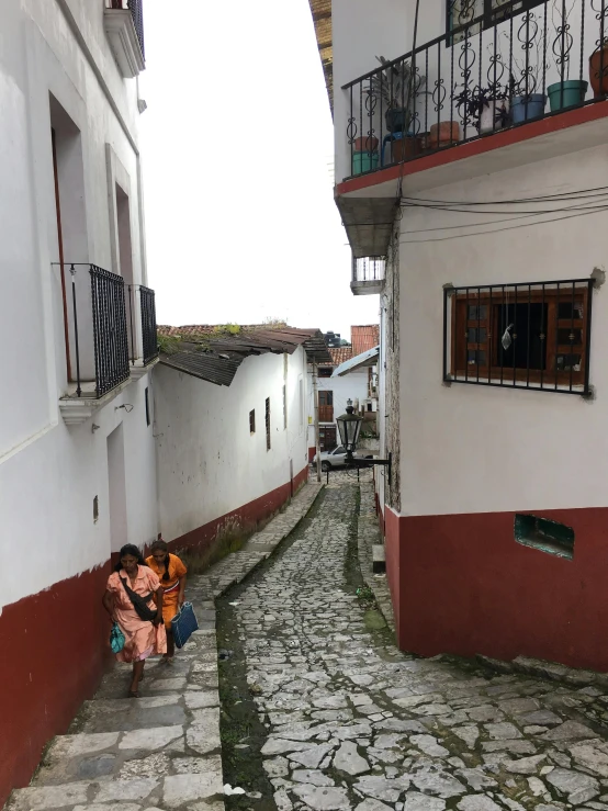 two women sitting on the curb of an alleyway