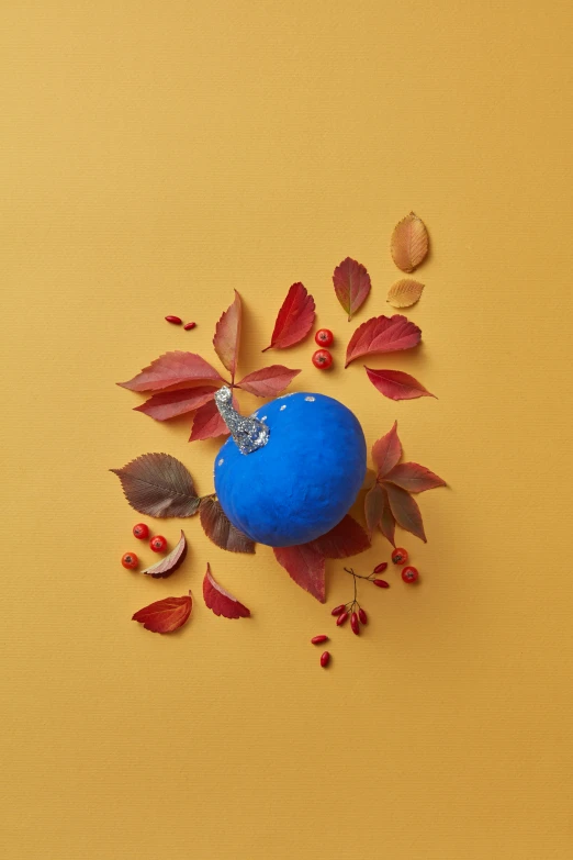 a blue ball surrounded by leafs on a yellow surface