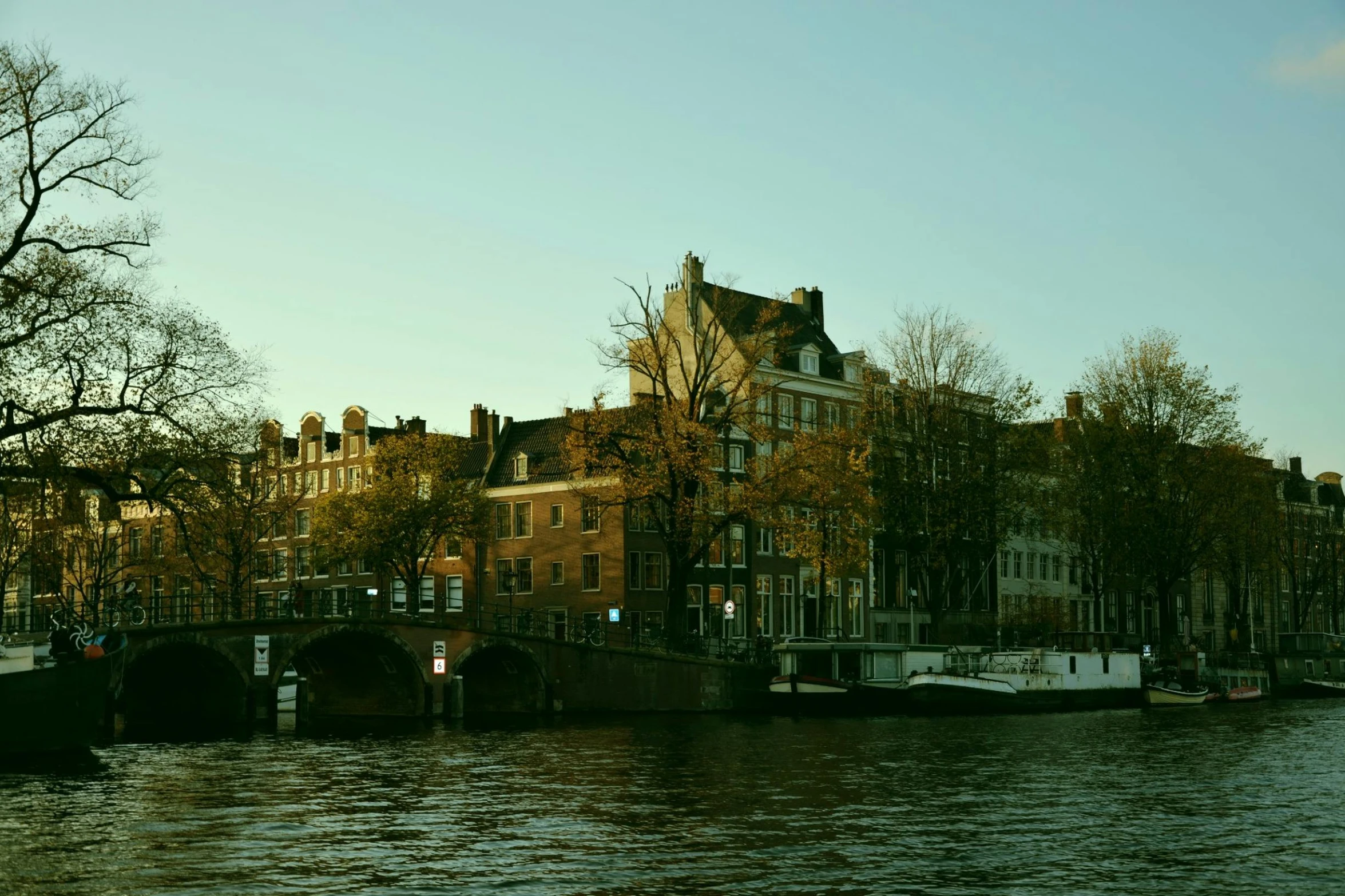 there is a building along the water with a bridge and buildings in the background