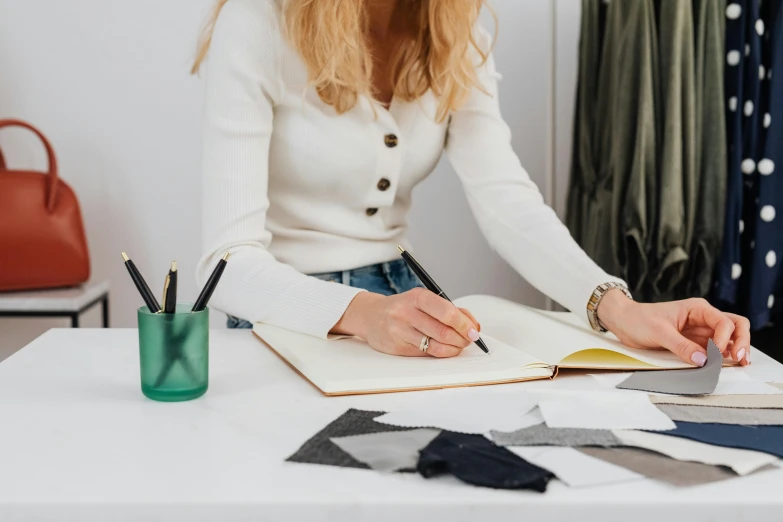 a person writing on paper in front of a book