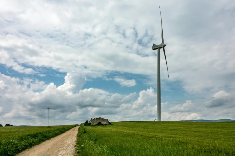 an old barn and wind mill stand on the side of a rural road