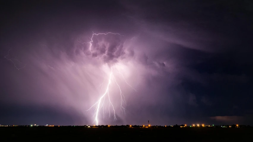 a large lightning streaks in the sky above a city