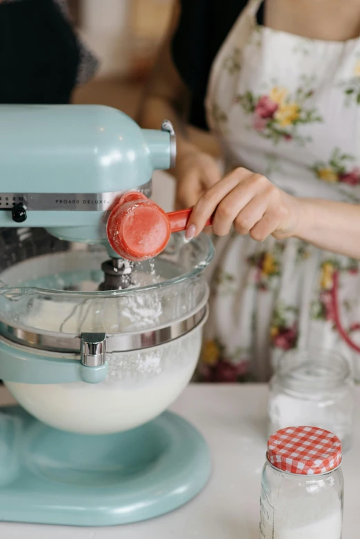 a woman is mixing some ingredients in a mixer