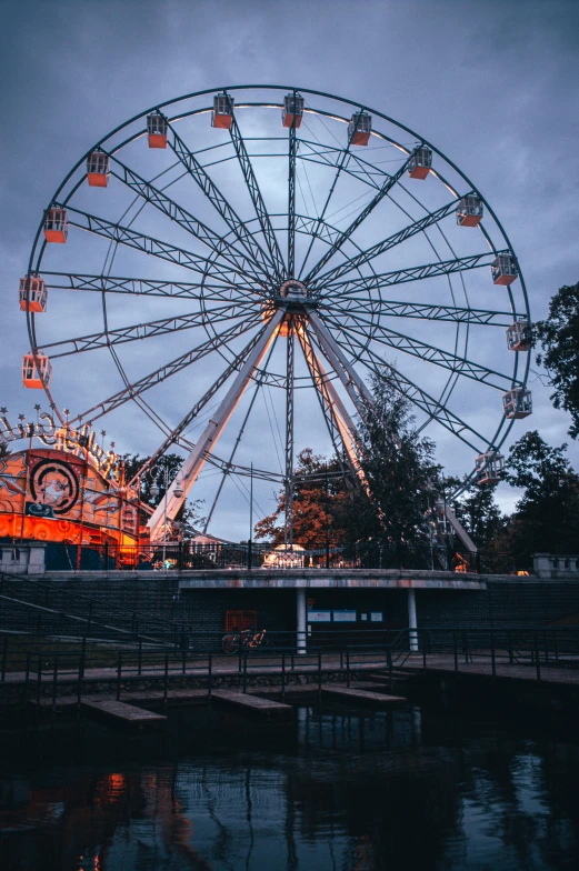 a large wheel sitting over a river next to a lush green field