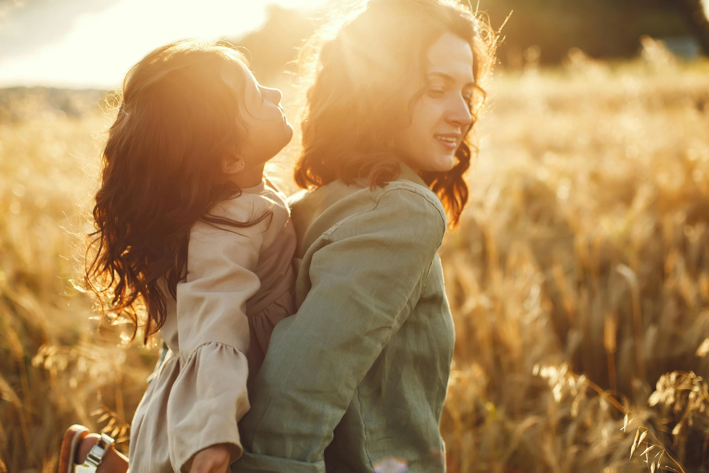 two young women are in a field at sunset