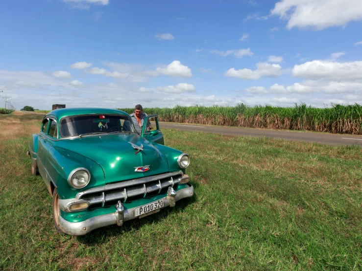 a person standing next to a green vintage car