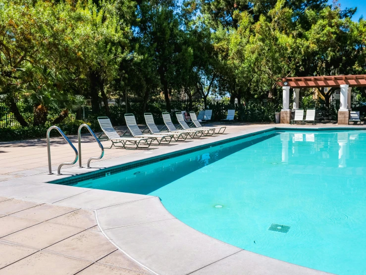 a swimming pool with lounge chairs on both sides