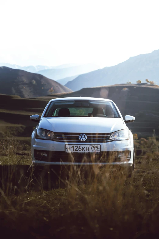 a white car is parked along a dirt road