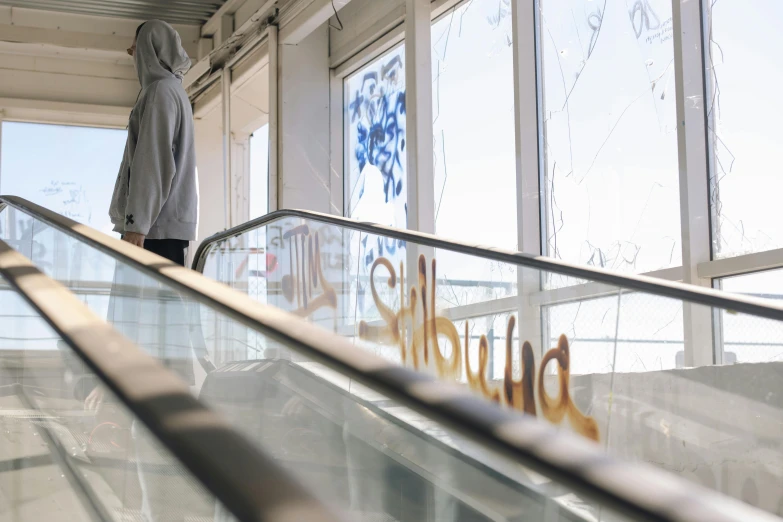 a male in grey jacket standing on an escalator and holding an umbrella