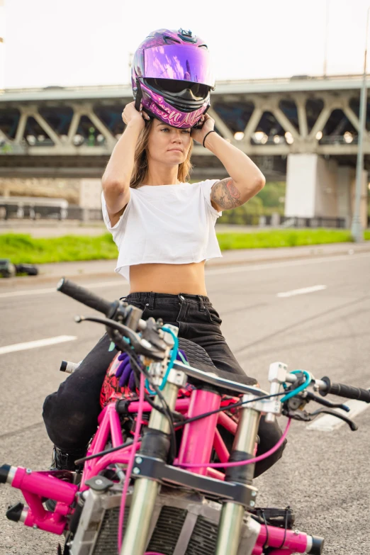 a woman with pink motorcycle gear on sitting at the back of a bike