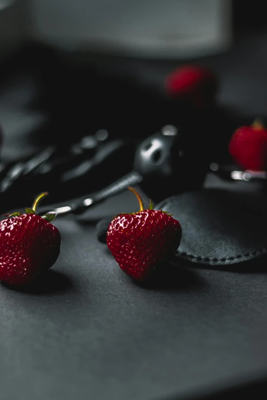 strawberrys on a black surface with scissors and tongs