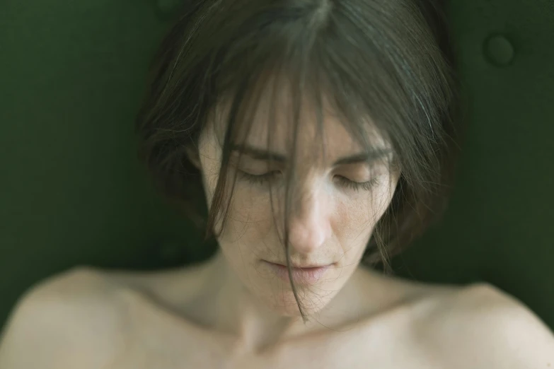 a woman with long hair looks down as she lies 