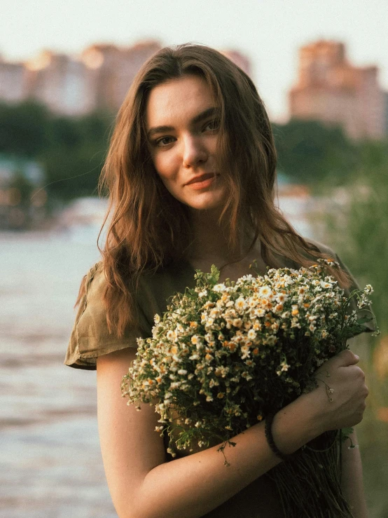 a young woman holds up a bouquet of wildflowers in her hands