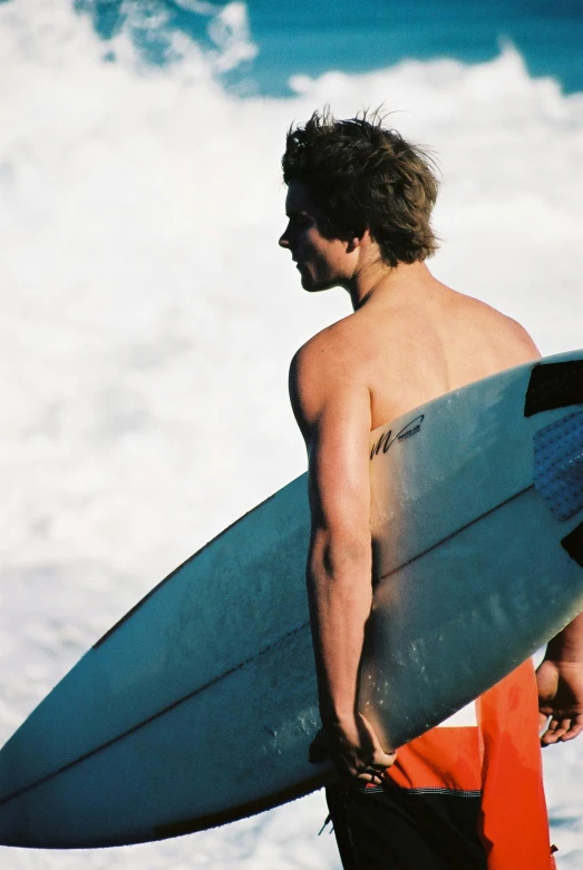 the man walks down the beach carrying his surfboard