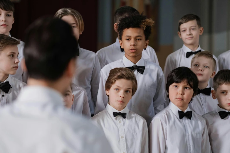 boys in white and black bow ties are standing in front of an audience