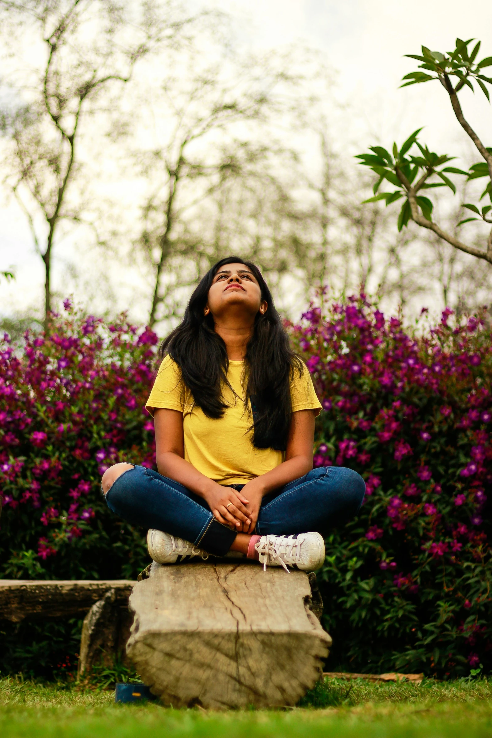 woman in yellow shirt sitting on stone and doing yoga