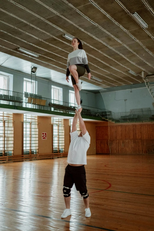 two people doing tricks in an indoor gymnasium