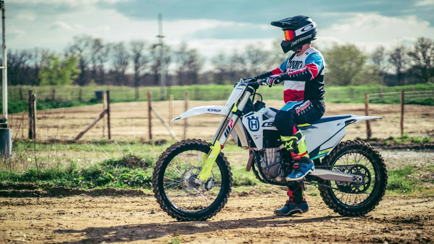 a person is standing on a motorcycle on dirt