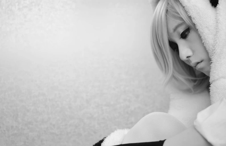 a girl sitting in front of a wall with teddy bear ears on