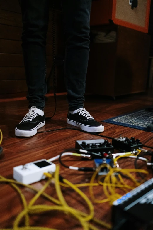 two feet standing on a hard wood floor near wires