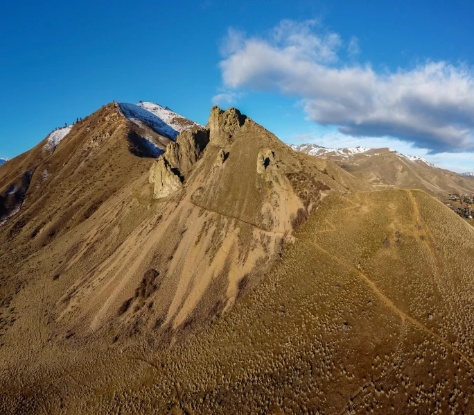 a brown mountainside with snow on the top and a blue sky