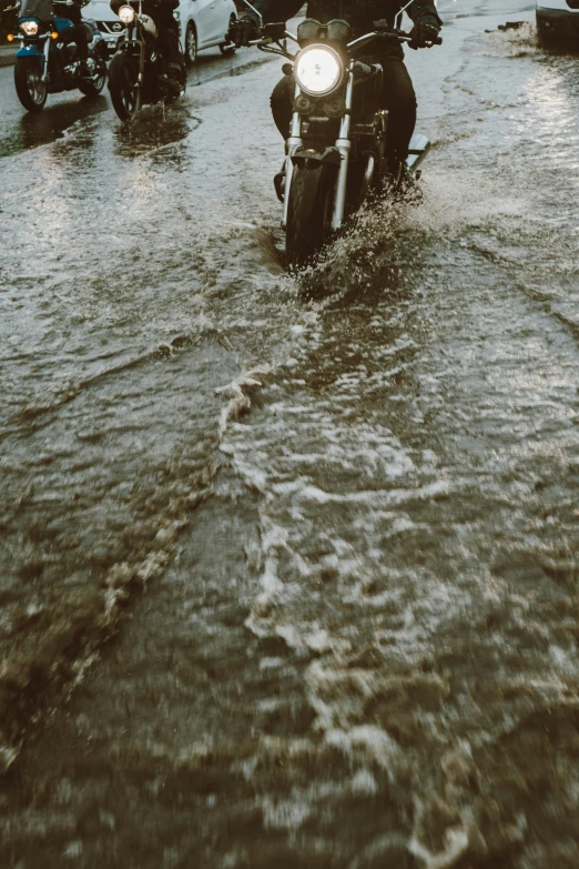 a black and white po of a motorcycle driving in a street full of parked motorcycles