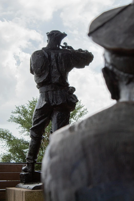 a statue of a soldier in a field with a building behind it