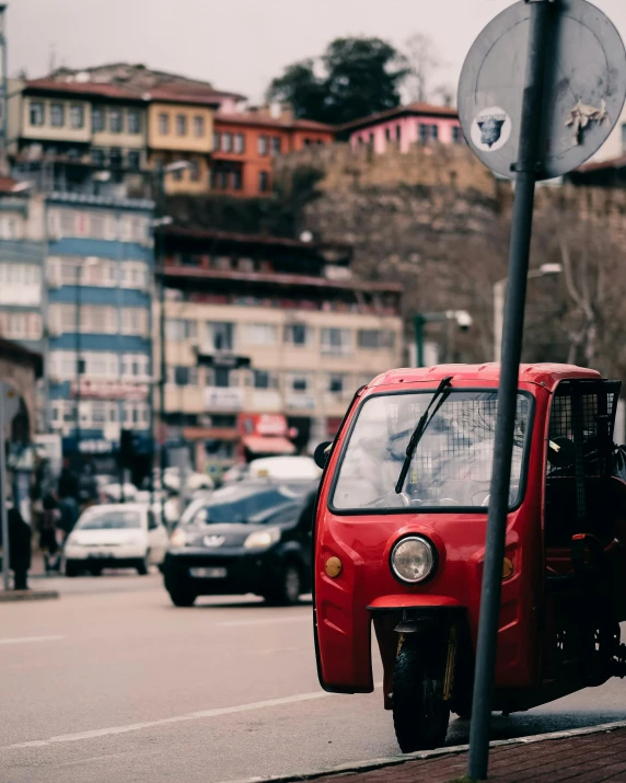 the small red vehicle is parked along the sidewalk