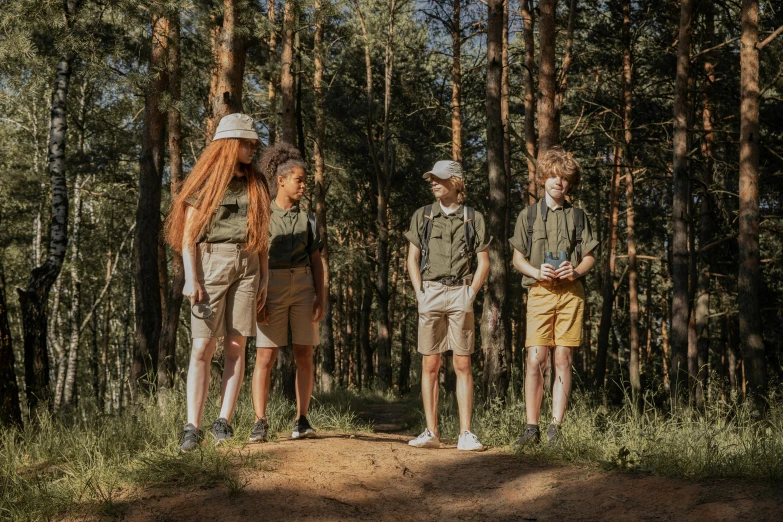 three young men stand on a trail in a wooded area