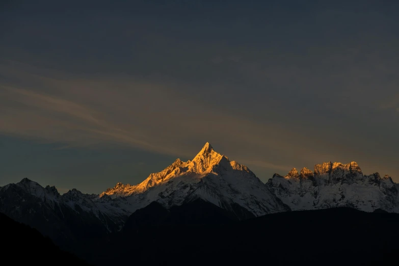 a snow capped mountain rises high into the dark sky