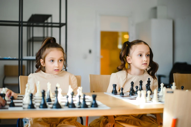 two children playing chess in front of a crowd