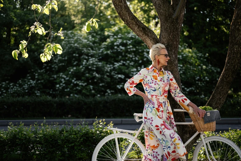 an older woman stands next to a bike in a city park