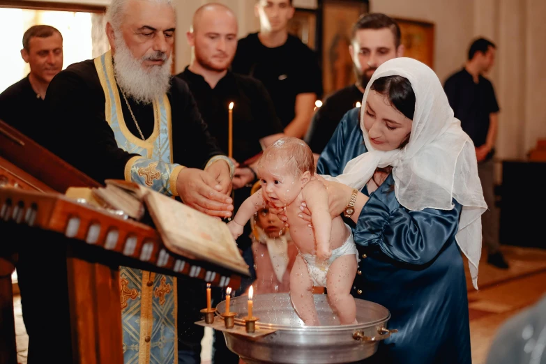 the priest is holding a young child in front of the altar