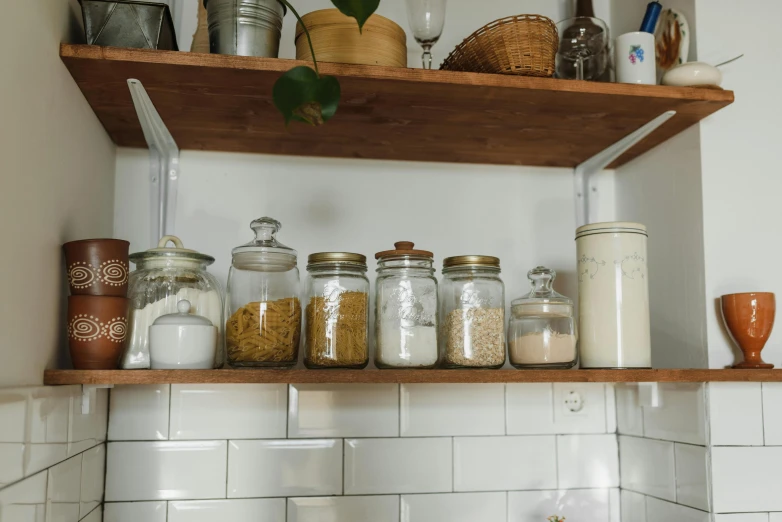 jars of various types and sizes sit on a shelf in a kitchen