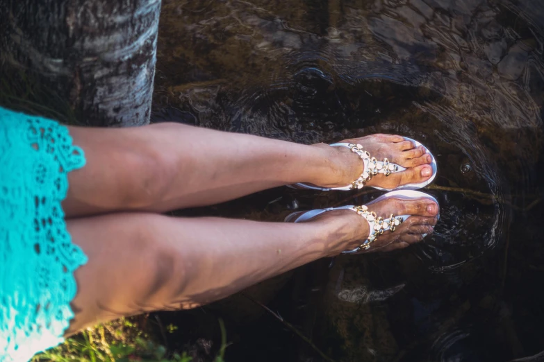 a woman in sandals standing near water