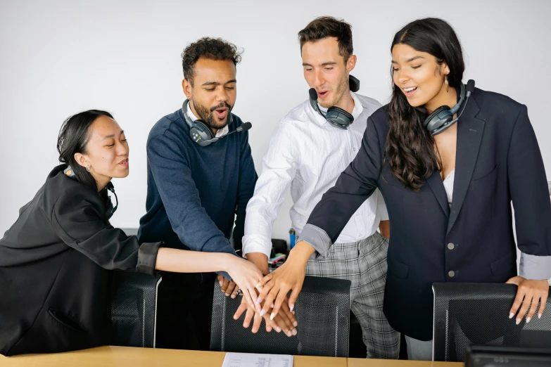 four smiling people with each other putting their hands in the center