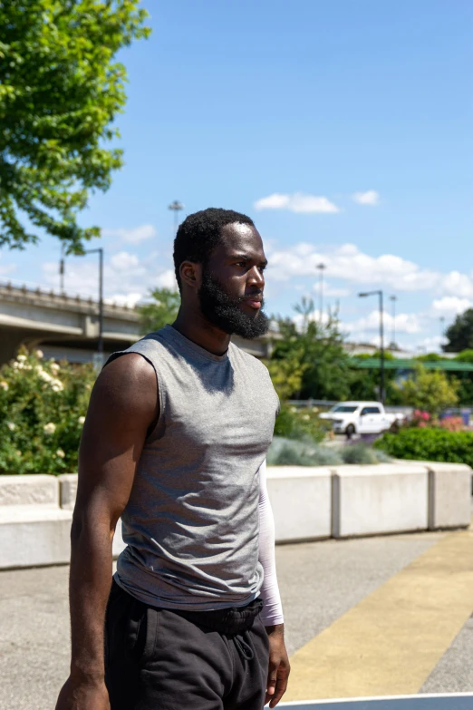 a black man in grey tank top on a street