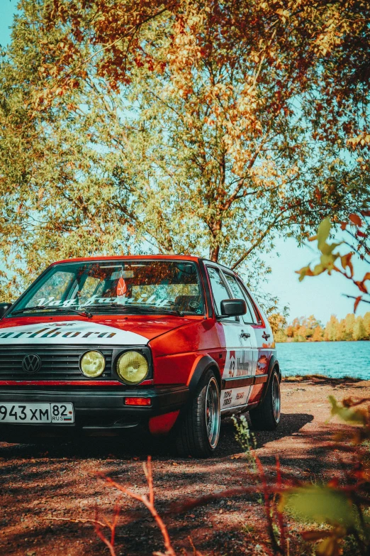 a red, vintage race car parked on some trees