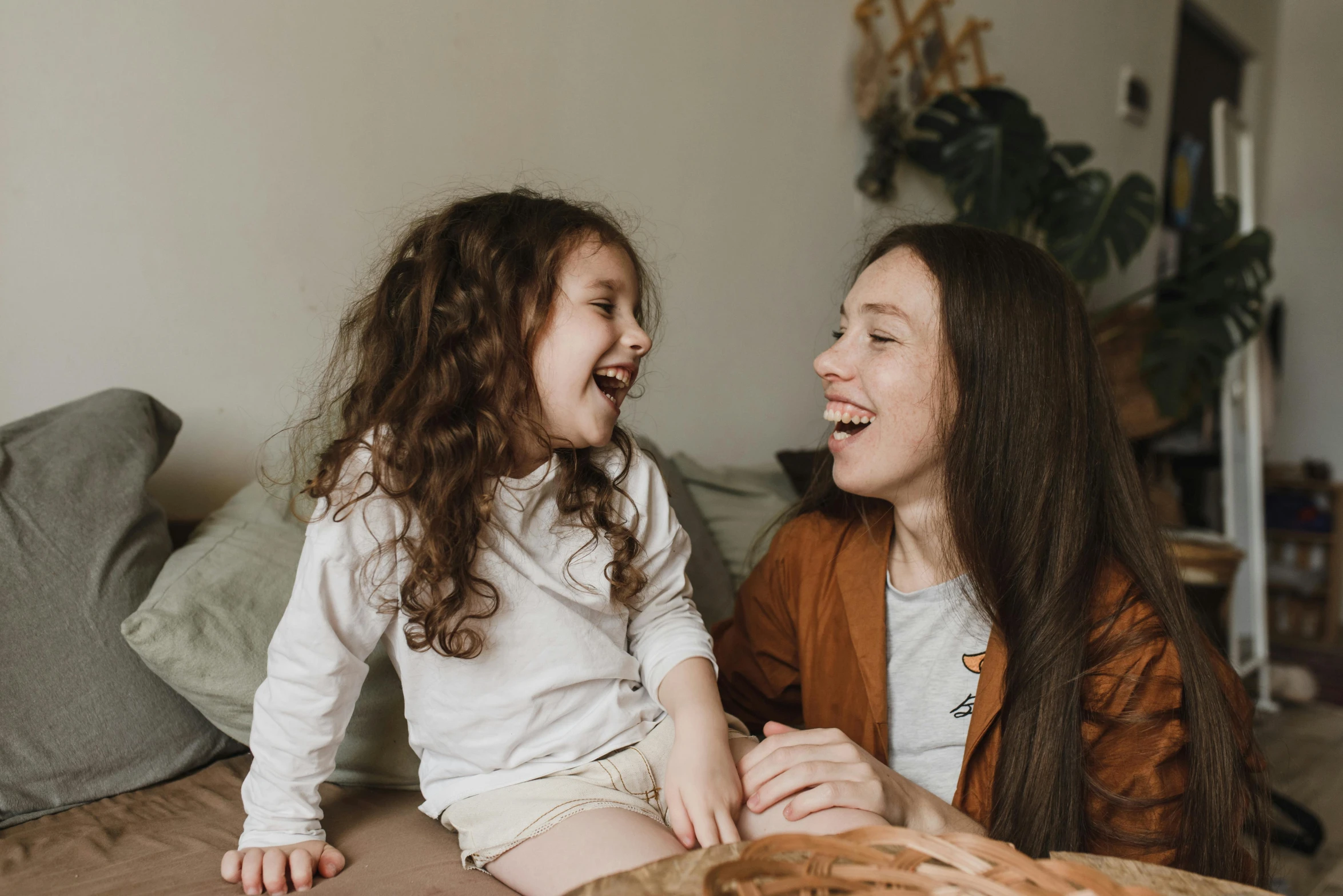 mother and daughter laughing on bed during family pography