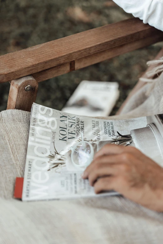 the arm of a chair that is holding a newspaper