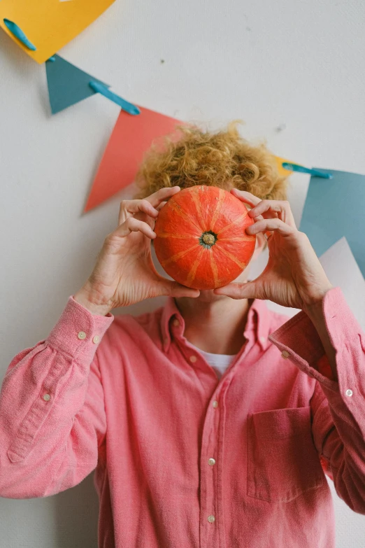 woman covering her eyes and holding an orange above her head