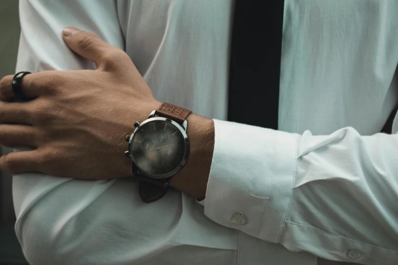 person wearing an old watch while wearing white dress shirt and tie