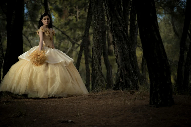 the beautiful bride wearing a yellow gown is walking through a forest