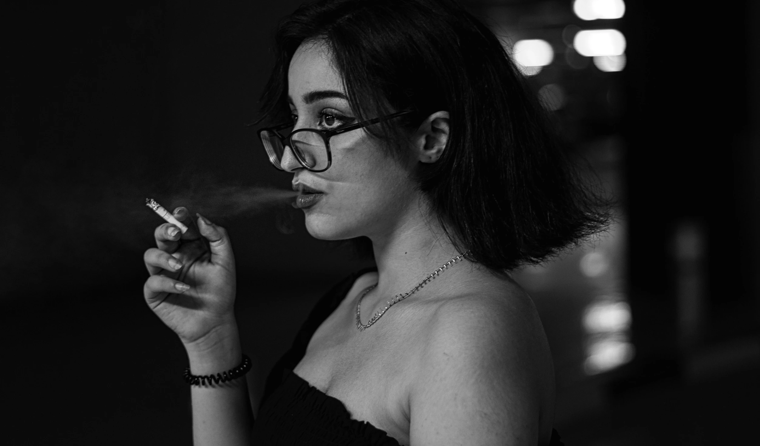 a woman holding a cigarette with the wind blowing through her hair