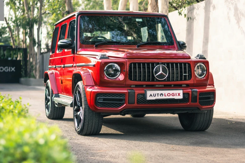a red mercedes benz g class is parked in the driveway