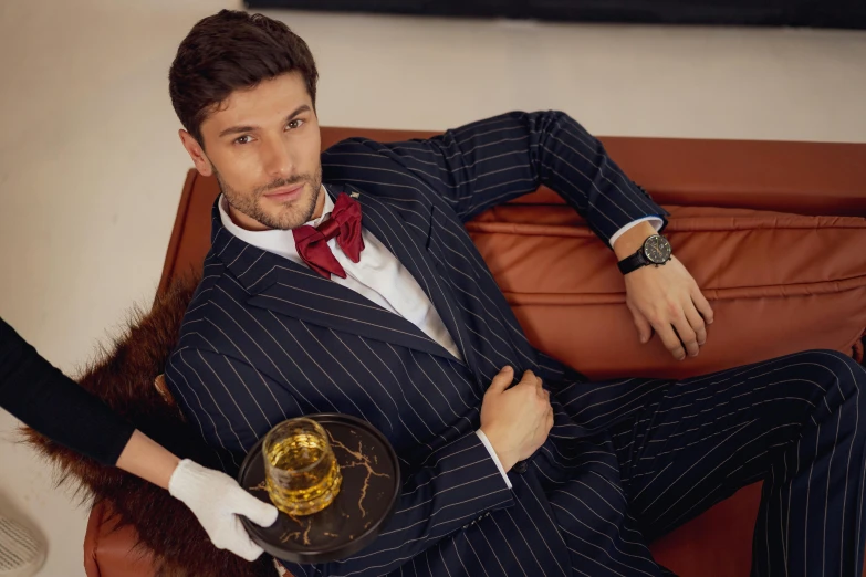 a man in a suit sitting on a leather chair holding a golden ball