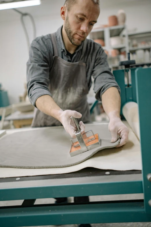 man in the process of making a felt floor mat